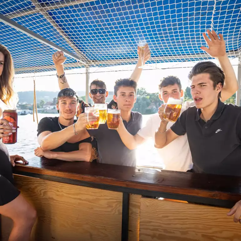 Group of people on board of a party boat having a good time on Vltava river.